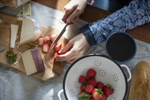 Измельчать клубнику и сыр на деревянной доске